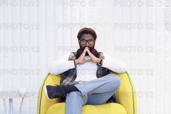 Pensive black man sitting in yellow chair