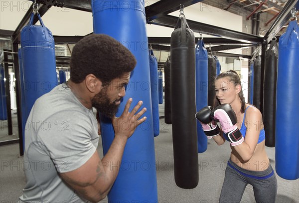 Man training woman using punching bag