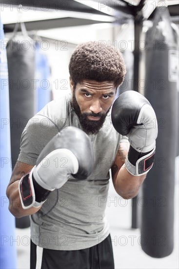 Portrait of Black man wearing boxing gloves in gymnasium