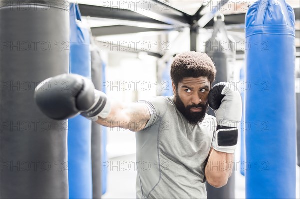 Portrait of Black man wearing boxing gloves in gymnasium