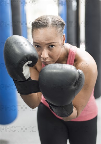 Portrait of Black woman wearing boxing gloves in gymnasium