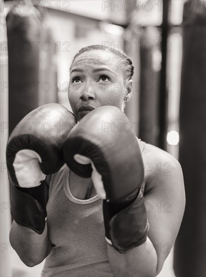 Portrait of Black woman wearing boxing gloves looking up
