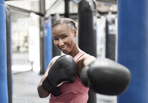 Portrait of smiling Black woman wearing boxing gloves in gymnasium