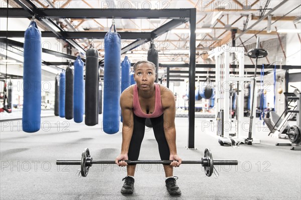 Black woman lifting barbell in gymnasium