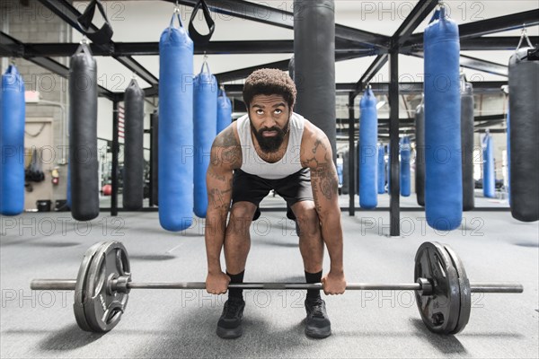 Black man lifting barbell in gymnasium