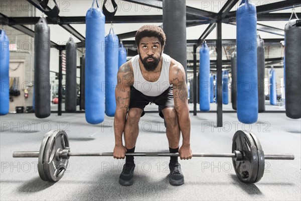 Black man lifting barbell in gymnasium