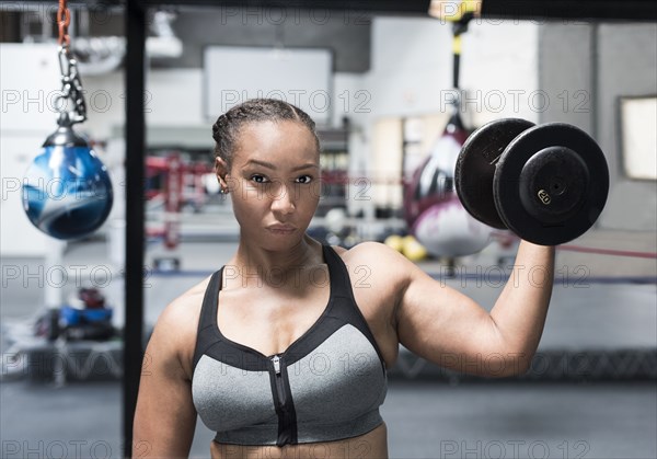 Black woman lifting dumbbell in gymnasium