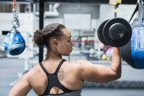 Black woman lifting dumbbell in gymnasium