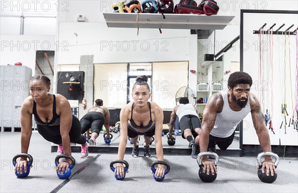 Man and women doing push-ups with kettlebells