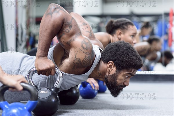Man and women doing push-ups with kettlebells