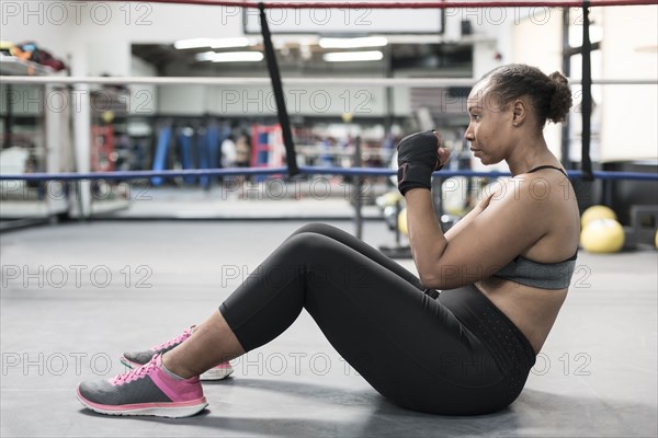 Black woman sitting on floor in boxing ring