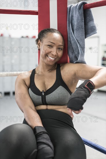 Black woman leaning in corner of boxing ring