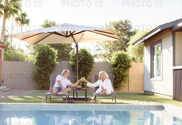 Caucasian couple toasting near swimming pool