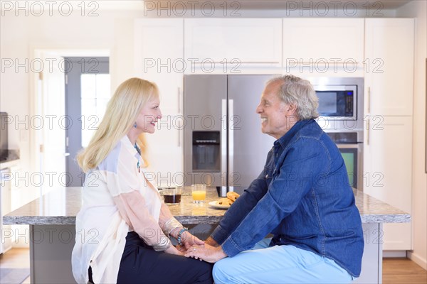 Caucasian couple holding hands in kitchen