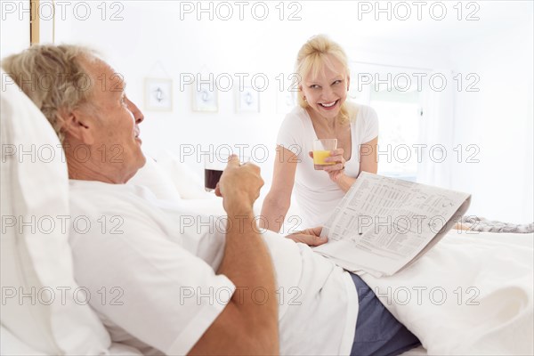 Caucasian couple drinking coffee and juice in bed