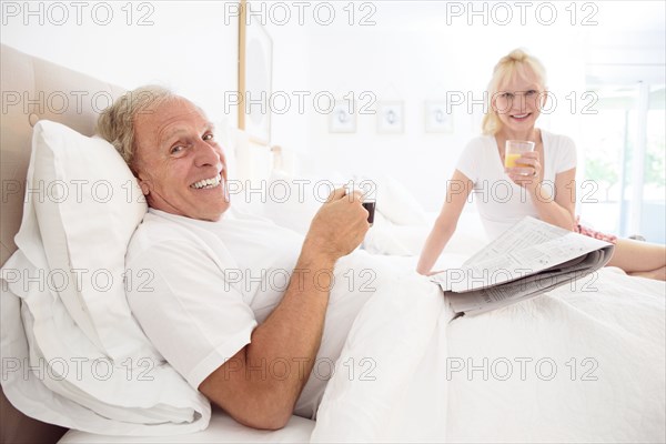 Caucasian couple drinking coffee and juice in bed