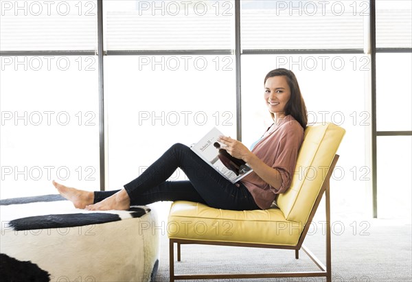 Mixed race woman sitting on chair reading book