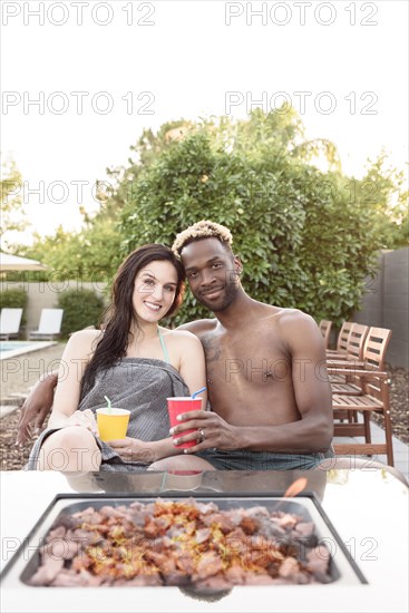 Portrait of smiling couple wrapped in towels near fire pit