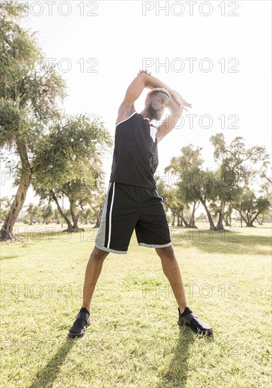 Black man stretching arms in park