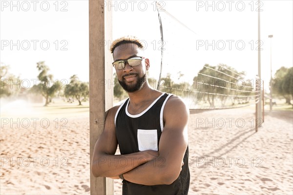 Portrait of smiling black man leaning on beach volleyball net