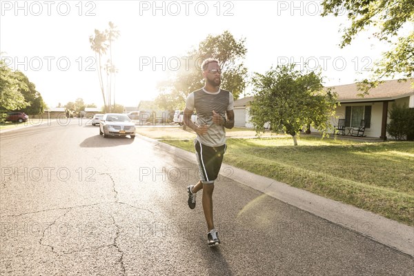 Black man running on street in neighborhood