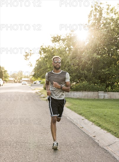 Black man running on street in neighborhood