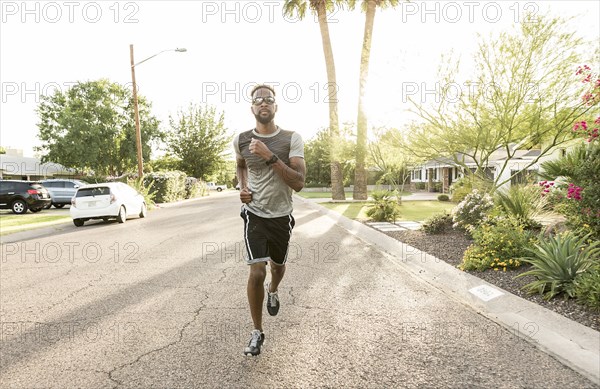 Black man running on street in neighborhood