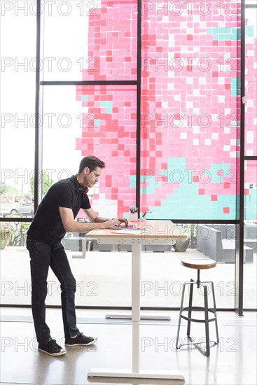 Caucasian man using a laptop at standing workstation