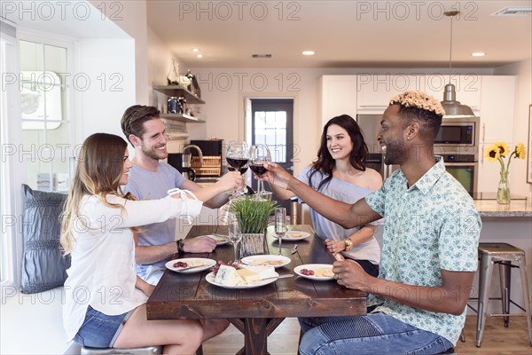 Friends eating cheese and toasting with red wine