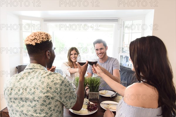 Friends toasting with red wine at table