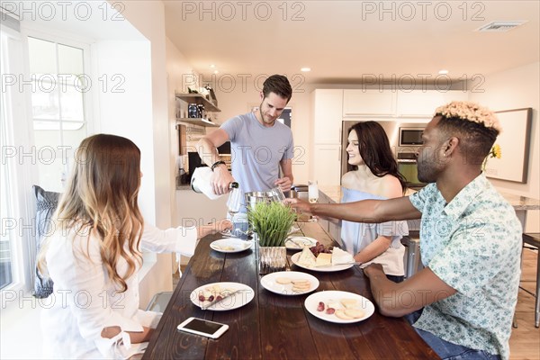 Man pouring champagne for friends at table