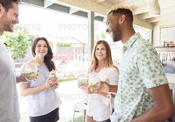 Smiling friends with cold drinks talking outdoors