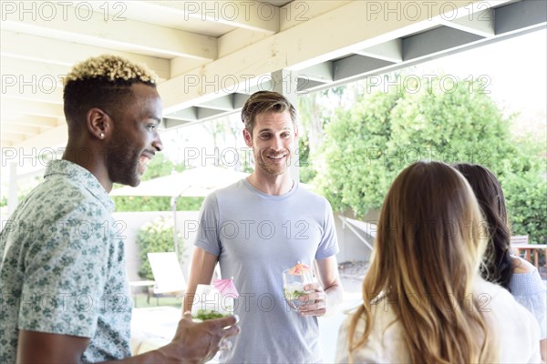 Smiling friends with cold drinks talking outdoors