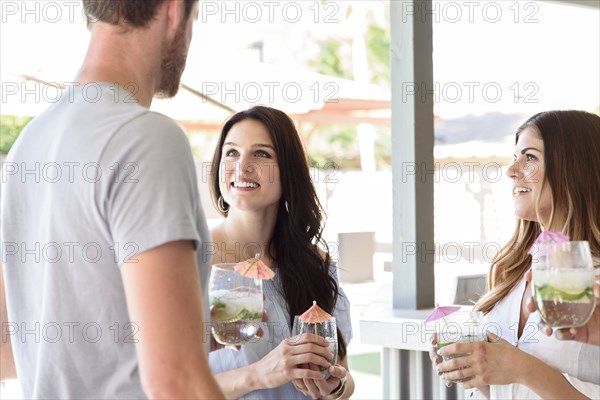 Smiling friends with cold drinks talking outdoors