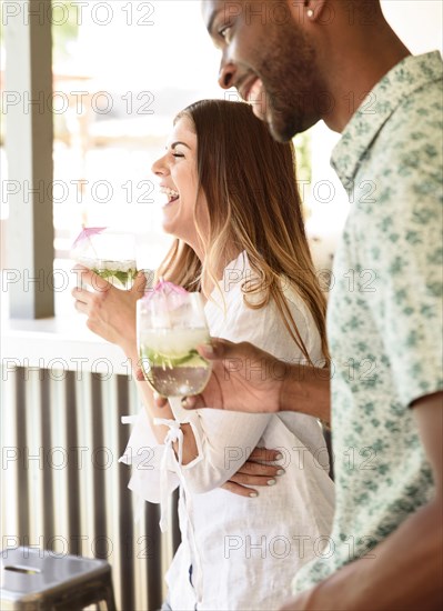 Smiling couple with cold drinks laughing outdoors