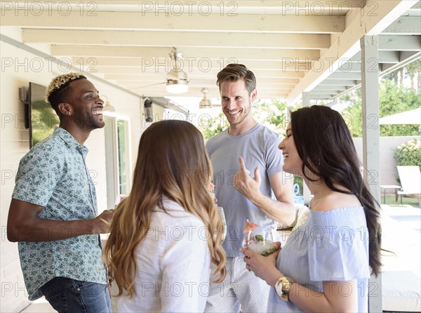 Smiling friends with cold drinks talking outdoors