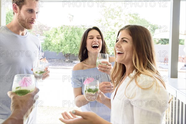 Smiling friends with cold drinks laughing outdoors