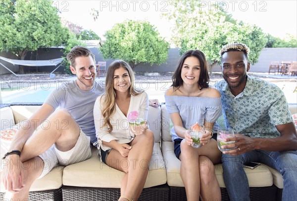 Portrait of smiling friends with cold drinks sitting outdoors