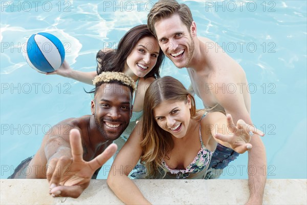 Portrait of smiling friends in swimming pool with basketball