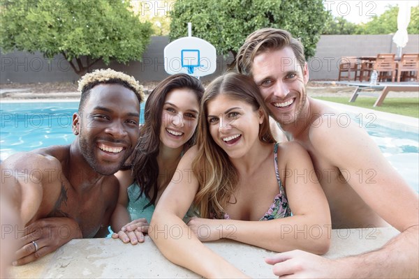 Smiling friends in swimming pool posing for selfie