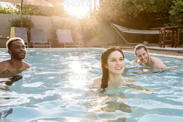 Smiling friends relaxing in swimming pool