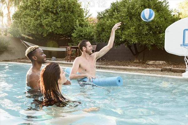 Friends watching man shooting basketball in swimming pool