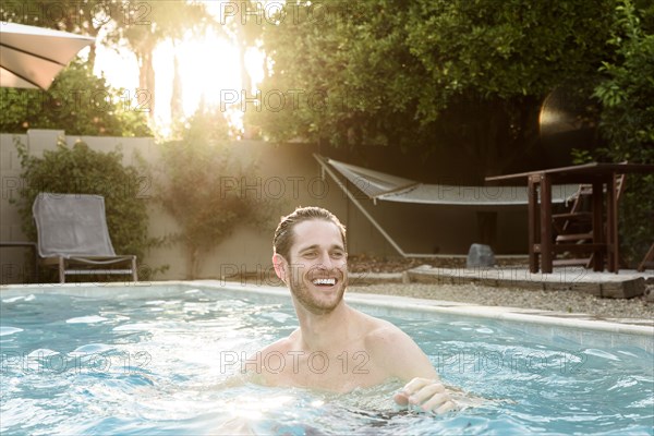 Smiling Caucasian man relaxing in swimming pool