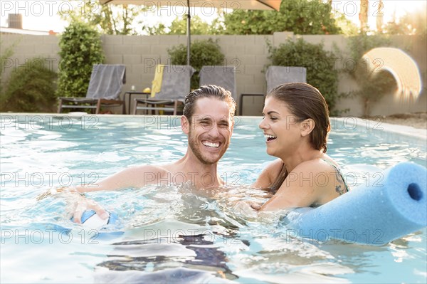 Smiling Caucasian couple relaxing in swimming pool