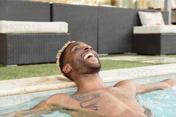 Smiling Black man relaxing in swimming pool