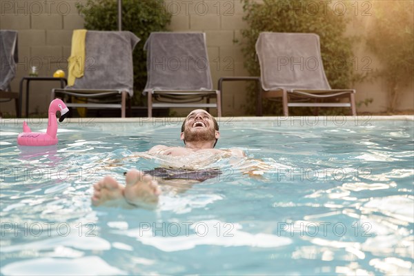 Smiling Caucasian man floating in swimming pool
