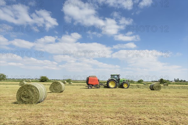 Caucasian man driving tractor baling hay