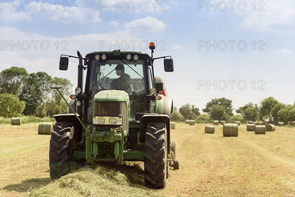 Caucasian man driving tractor baling hay