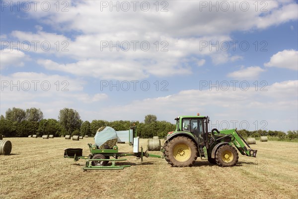 Caucasian man driving tractor baling hay