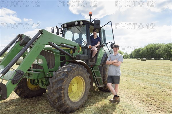 Smiling Caucasian couple posing near tractor